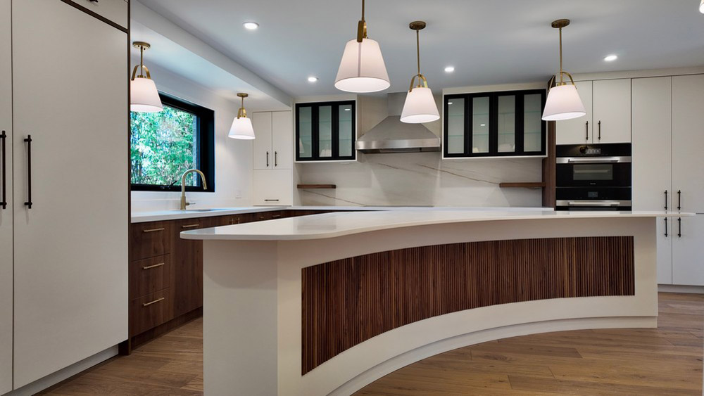 Curved quartz island facing the walnut run and Miele wall ovens