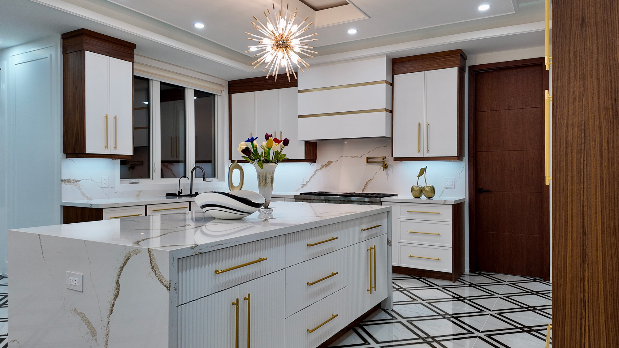 Elegant white kitchen with walnut accents, brass hardware and waterfall island