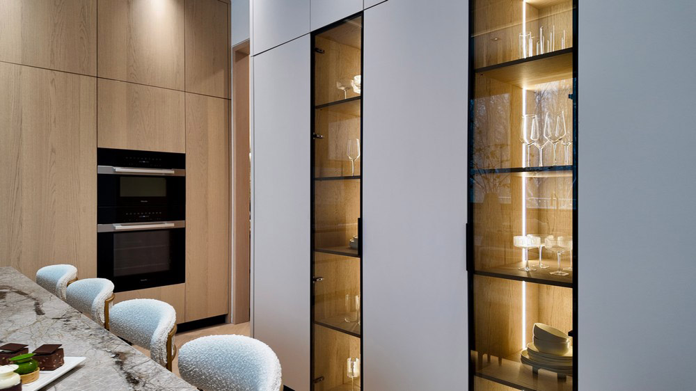 Miele ovens beside illuminated glass display cabinets