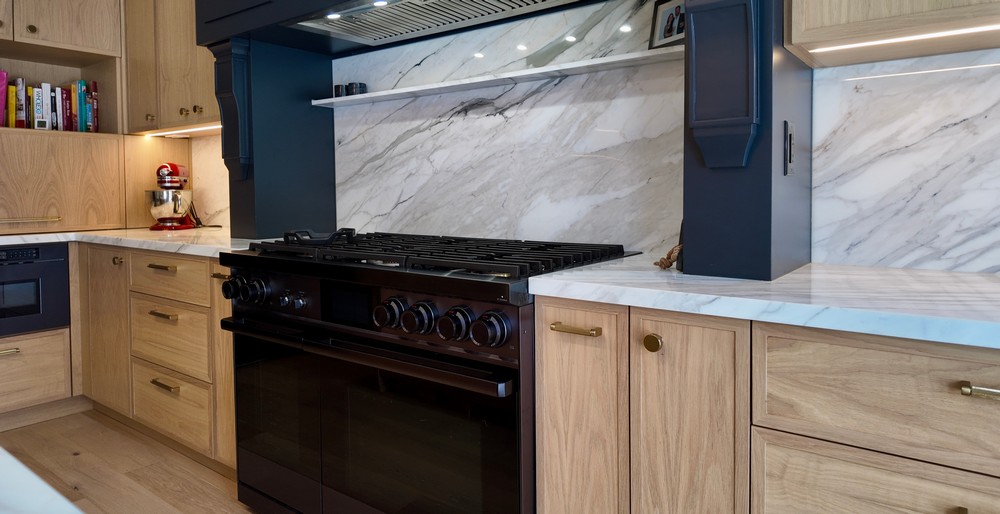 Dacor professional gas range framed by the custom hood and marble slab