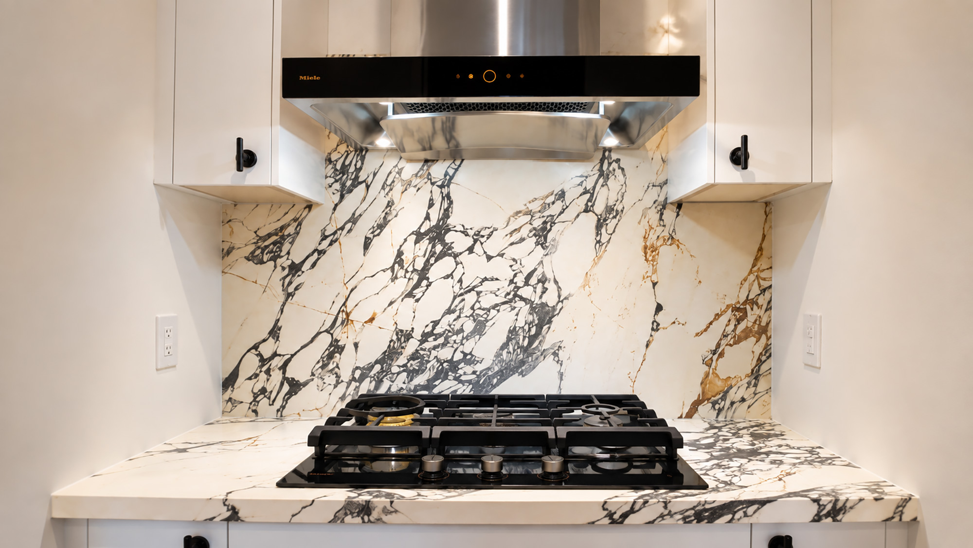 Soft sage green kitchen with veined stone backsplash and herringbone flooring