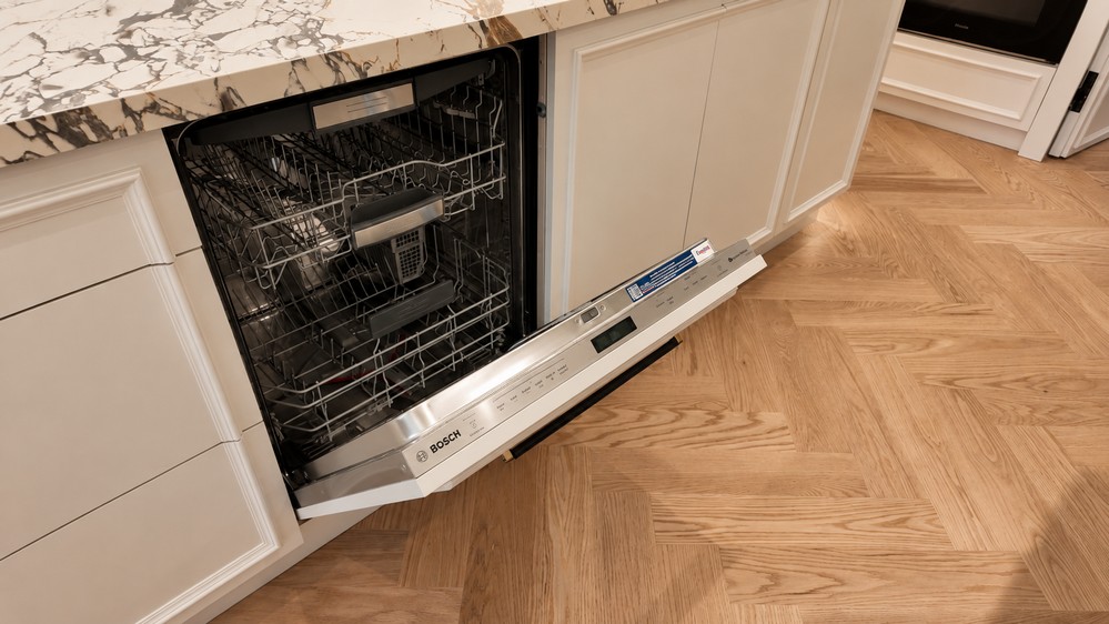 Bosch panel-ready dishwasher open in the island above herringbone flooring