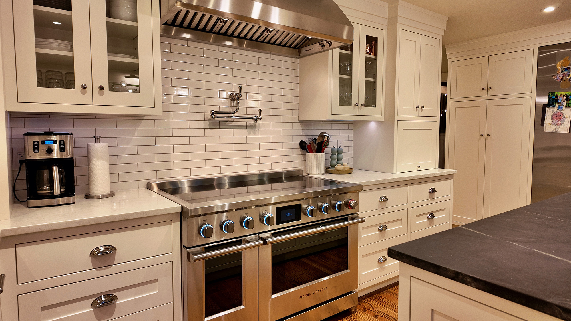 Warm transitional kitchen with white cabinetry, subway tile and dark stone island