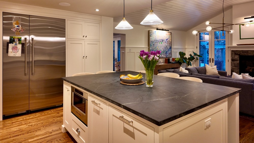 Stainless side-by-side refrigerator alongside the island and open living space