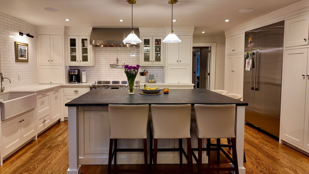 Island seating facing the range wall with subway tile and glass-front uppers