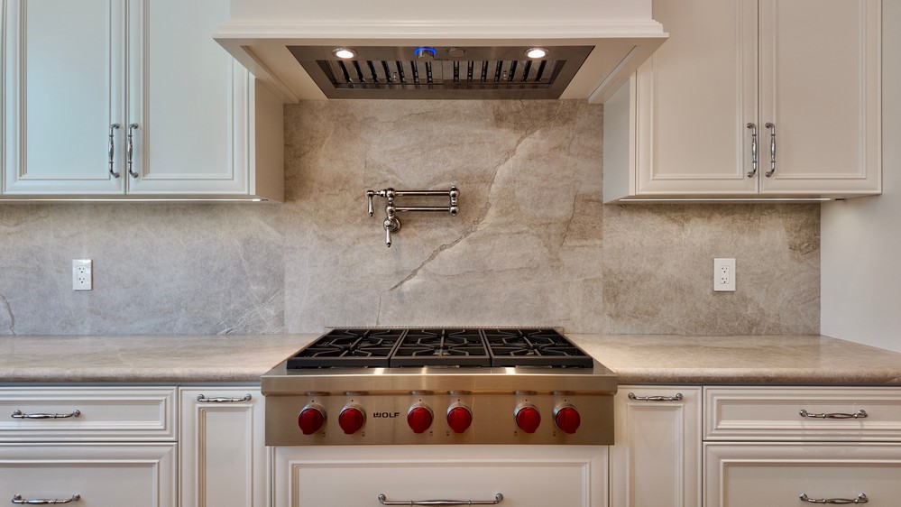 Wolf gas rangetop centred beneath the Elica hood and stone backsplash