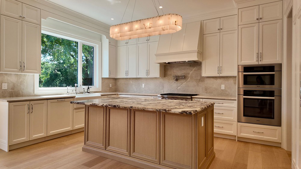 Stone-topped island facing the farmhouse sink and Miele wall ovens