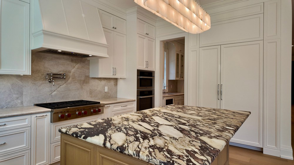 Veined stone island surface with the Wolf rangetop beyond