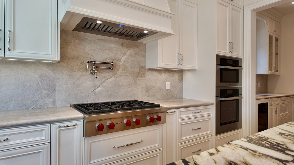 Wolf gas rangetop beneath the custom hood with Miele ovens to the right